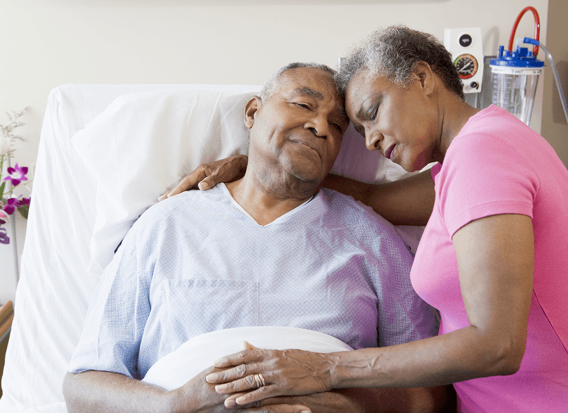 Elderly patient with their loved one comforting them in hospital bed